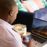 Black man freelancing on laptop in cozy room