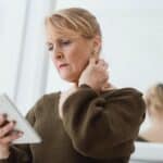 Concerned mature woman using tablet against mirror