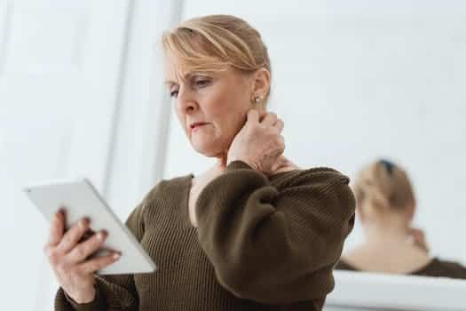 Concerned mature woman using tablet against mirror