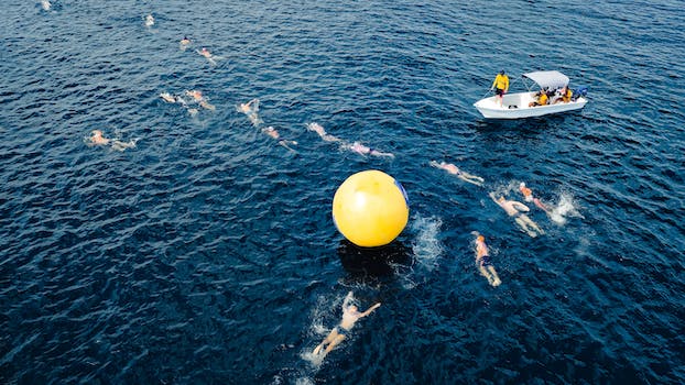 Aerial view of swimmers taking park in race and swimming around big yellow inflated ball in sea water