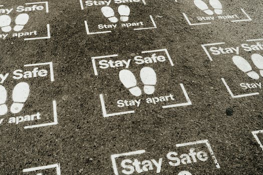 From above white sign of feet and inscription Stay Safe Stay Apart painted on asphalt road during coronavirus outbreak