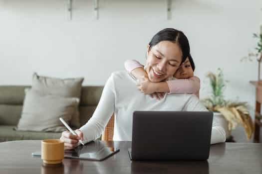 Happy mother working from home and little daughter hugging mom