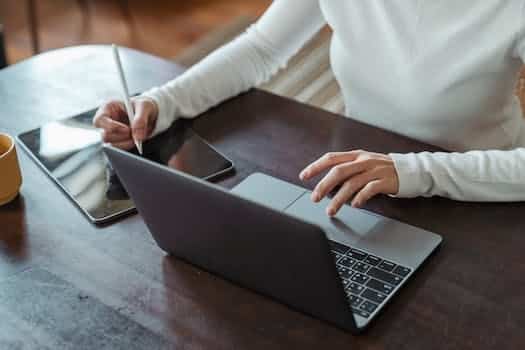 Crop faceless female entrepreneur doing multitasking work on different devices