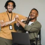 Smiling black coworkers holding hands in studio