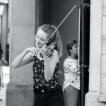 A woman playing the violin in front of a building