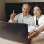 Positive colleagues of different aged using laptop in modern workspace